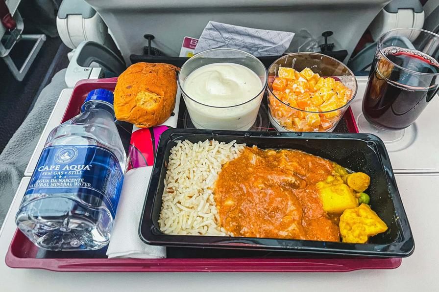 Qatar Airways economy hot meal with rice, curry, salad, fruit, and red wine